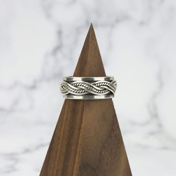 A Large Celtic Knot Spinner Ring resting on top of a wooden block.