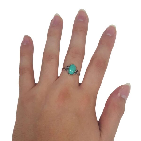 A woman's hand holding the Turquoise Triquetra Ring.