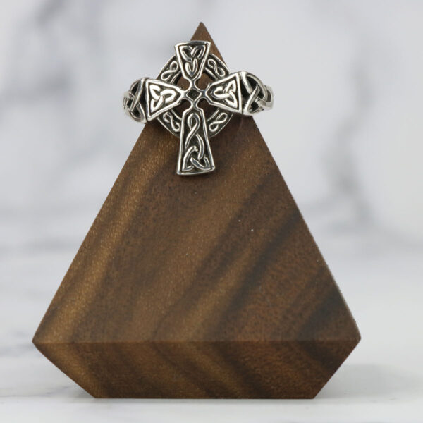 Celtic cross ring with a Two Tone Eternity Knot Band on a wooden stand.
