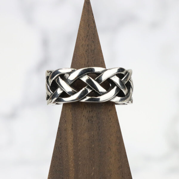An Interlacing Endless Knot Ring with an endless knot design resting on a wooden base.
