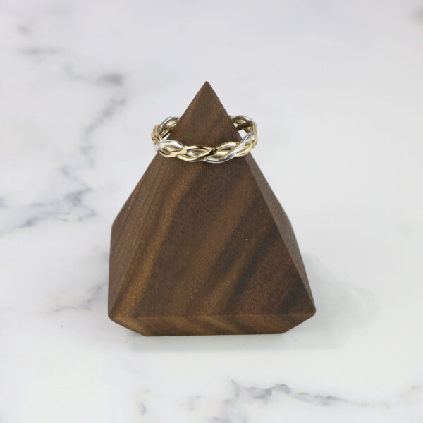 A wooden pyramid with a gold ring on top and a Two Tone Eternity Knot Band.