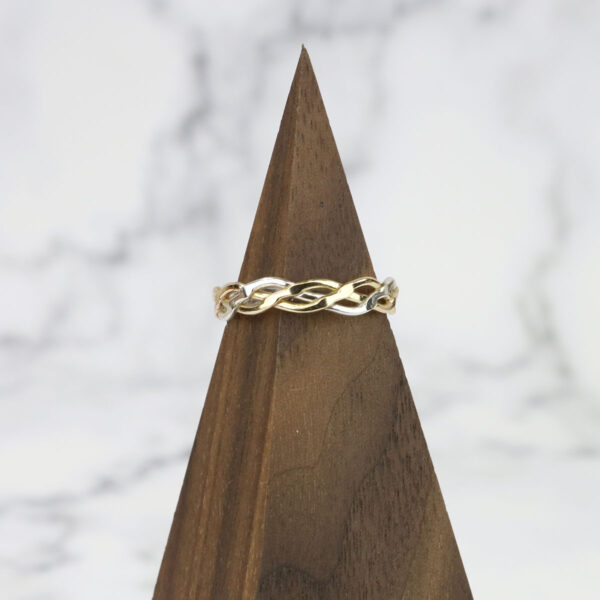 A gold ring with diamonds on top of a Two Tone Eternity Knot Band.