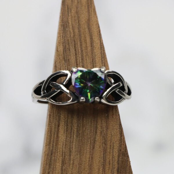 A Mystic Crystal Celtic Knot Heart Ring with a green stone.