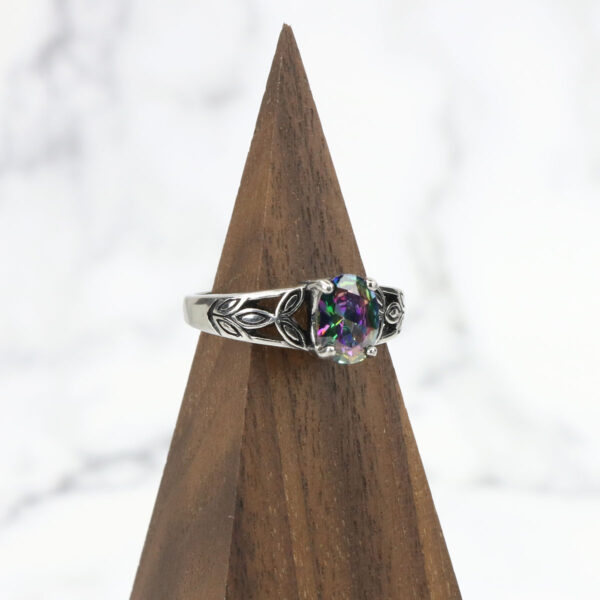 A Mystic Crystal Stainless Steel Ring with a multi colored stone on top of a triangle.