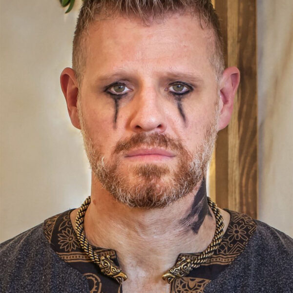A man with a Celtic tattoo on his face and a Celtic Griffin Neck Torc around his neck.