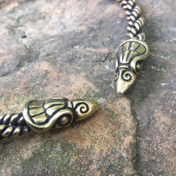 A pair of braided Celtic Raven Neck Torc bracelets on a rock.