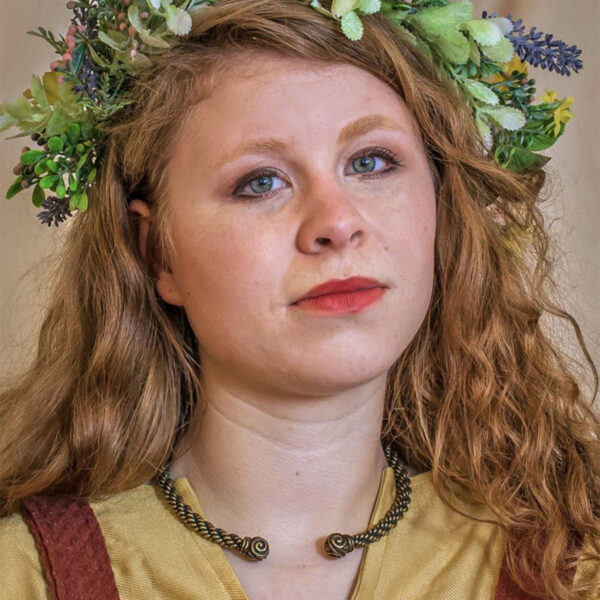 A young woman wearing a flower crown, adorned with a Celtic Triskelion Neck Torc.