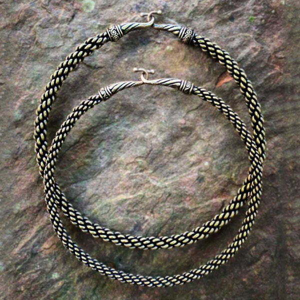 A pair of Viking Neck Torc-inspired braided hoop earrings on a rock.