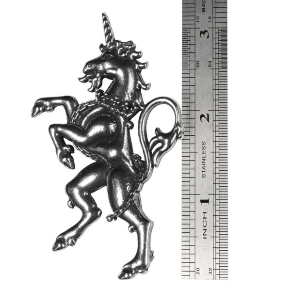 A silver Unicorn Rampant Kilt Pin/Brooch is standing next to a ruler adorned with a brooch.