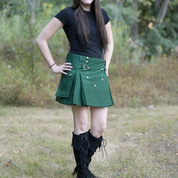 A woman wearing a green Ladies Wilderness Mini Kilt and black boots.