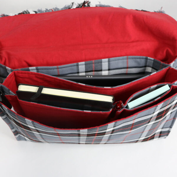 A Tartan Folio - Poly/Viscose Wool Free messenger bag in red and gray plaid, featuring a book inside.