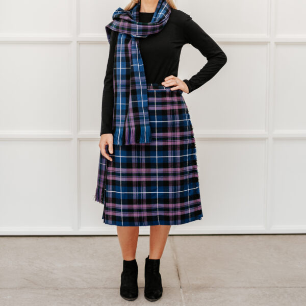 A woman celebrate National Tartan Day, wearing a blue and purple tartan skirt and scarf.