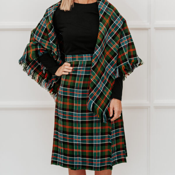 A woman in a plaid skirt and a scarf, wearing a Quality Wool Blend Kilt with Matching Tartan Flashes and FREE Kilt Hanger.