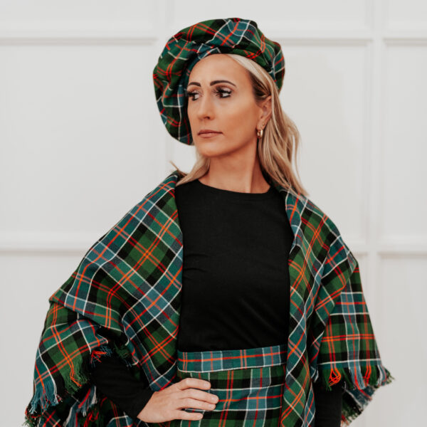 A woman in a green plaid outfit, showcasing the Quality Wool Blend Kilt with Matching Tartan Flashes and FREE Kilt Hanger style.