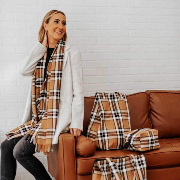 A woman sitting on a couch with plaid scarfs and a Tartan Purse - Poly/Viscose Wool Free.