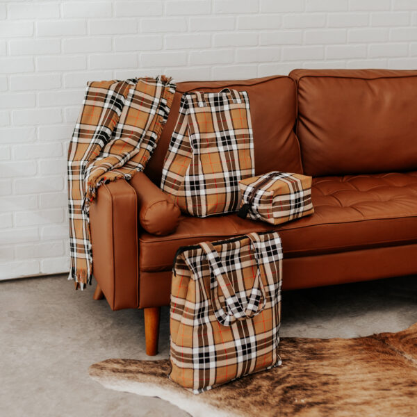 A brown leather couch with plaid blankets on it.