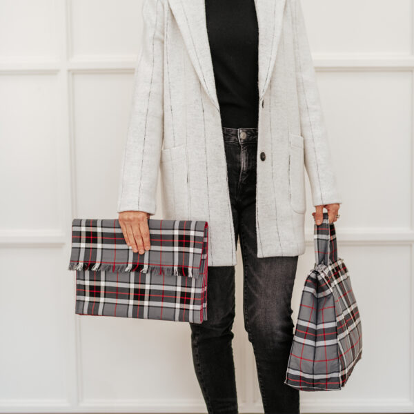 A woman donning a plaid coat and carrying a Tartan Purse - Poly/Viscose Wool Free.