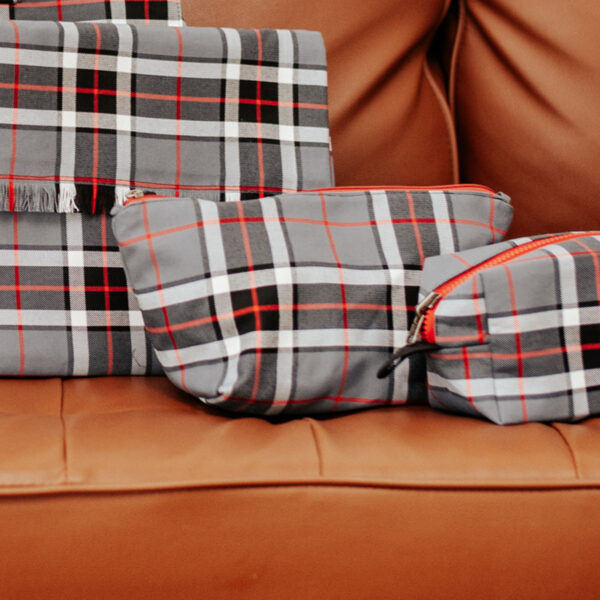 A collection of Tartan Zipper Pouch - Poly/Viscose Wool Free 80/20 on a couch.