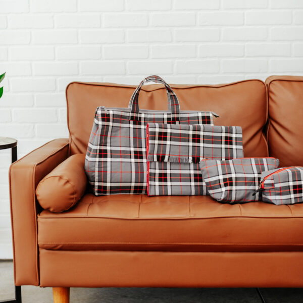 A brown couch with Tartan Folio - Poly/Viscose Wool Free bags and a plant on it. The Tartan Folio - Poly/Viscose Wool Free bags have a Tartan Folio design, made with Poly/Viscose wool-free material.