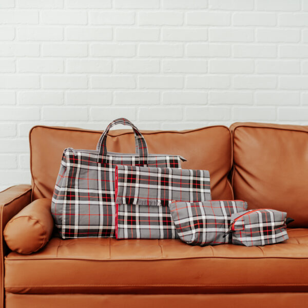 A Tartan Purse - Poly/Viscose Wool Free sitting on a brown leather couch.