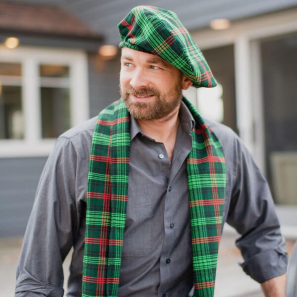 A man wearing a green and red tartan hat and scarf.
