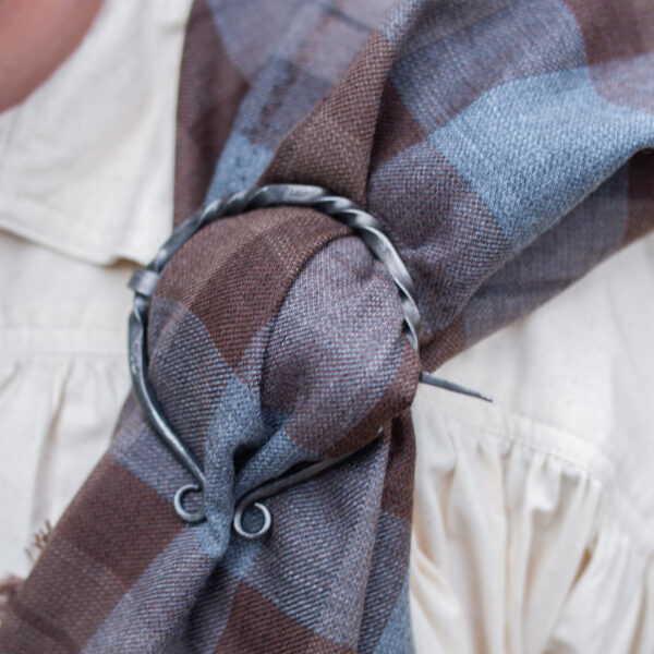 A man is wearing a plaid scarf with a ring on it.