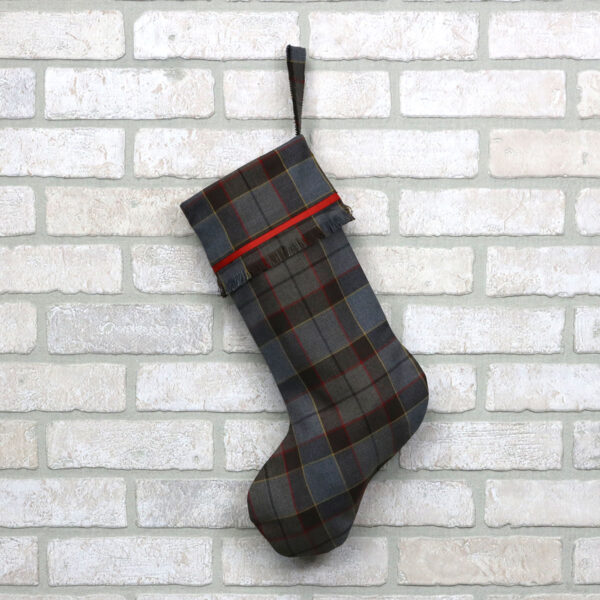 An Outlander All Tartan Stocking - Premium 13oz Wool hanging on a brick wall.