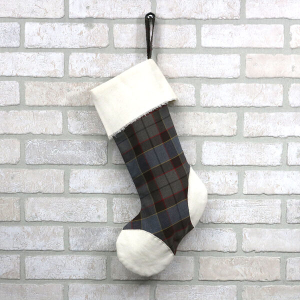 An OUTLANDER Tartan With Toes Stocking - Premium 13oz Wool hanging on a brick wall.