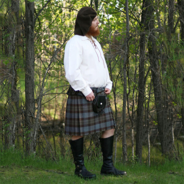 A man in an Outlander Tartan Phillabeg - Homespun Wool Blend kilt standing in a field.