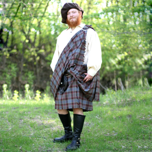 A man in an OUTLANDER Great Kilt Poly/Viscose Tartan is standing in the woods.