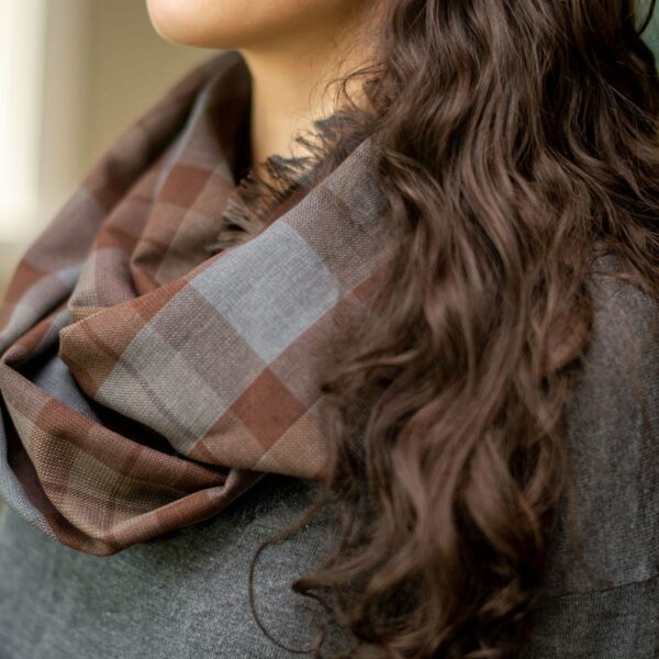 A woman wearing a Tartan OUTLANDER Wool Free infinity scarf in brown plaid.