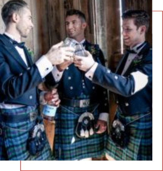 A group of men in kilts celebrating with a glass of wine.
