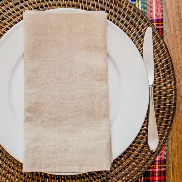 A white plate with a knife and fork on a Reversible Tartan Placemat - Homespun Wool Blend.