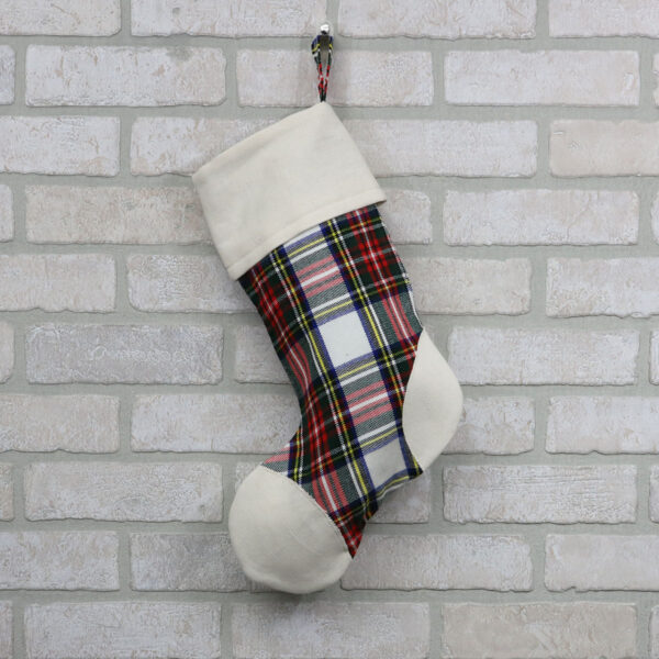 A Tartan Stocking with Toes - Homespun Wool Blend hanging on a brick wall.