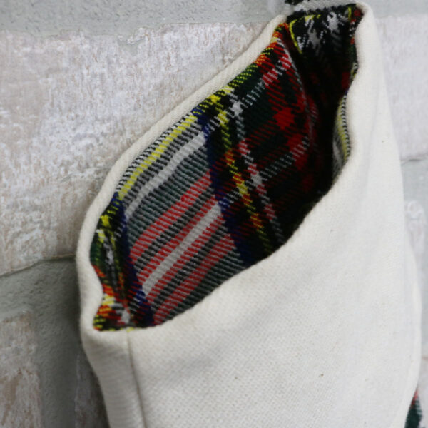 A Tartan Stocking with Toes - Homespun Wool Blend hanging on a brick wall.