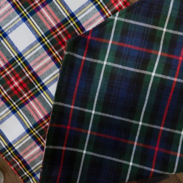 Two Reversible Tartan Table Runners – Homespun Wool Blend, made of homespun fabric, on top of a wooden table.