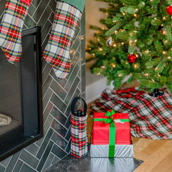 A cozy fireplace adorned with stockings and a festive Christmas tree showcasing the beautiful Tartan Tree Skirt - Homespun Wool Blend.