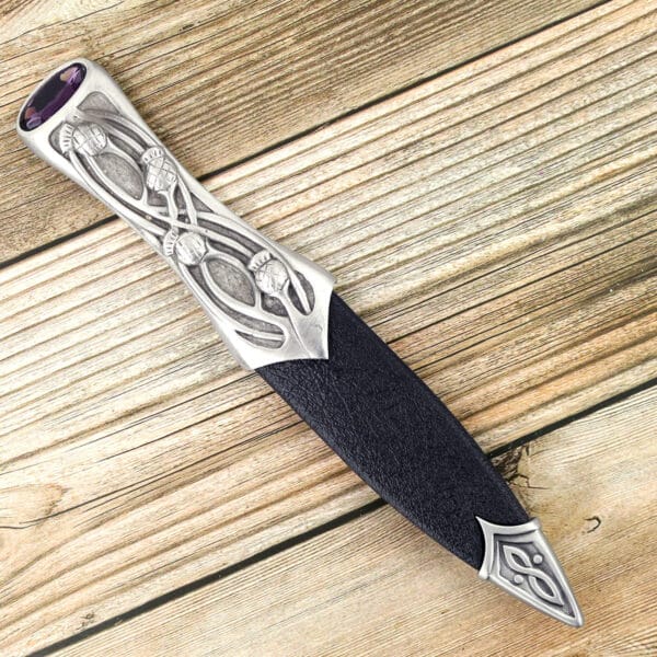 A silver Pewter Scottish Thistle Knot Sgian Dubh knife on a wooden table.