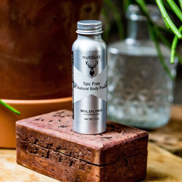 A bottle of Nutdust -Wildling sits on top of a wooden box, surrounded by the untamed essence of the Wildling.