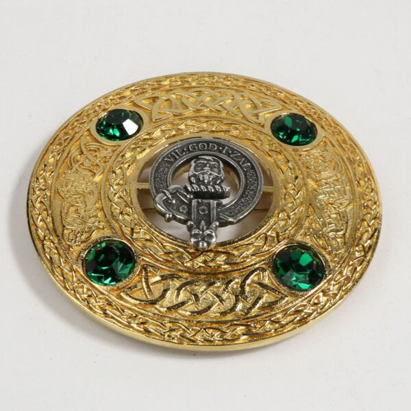 A brooch with a scottish crest and green stones.