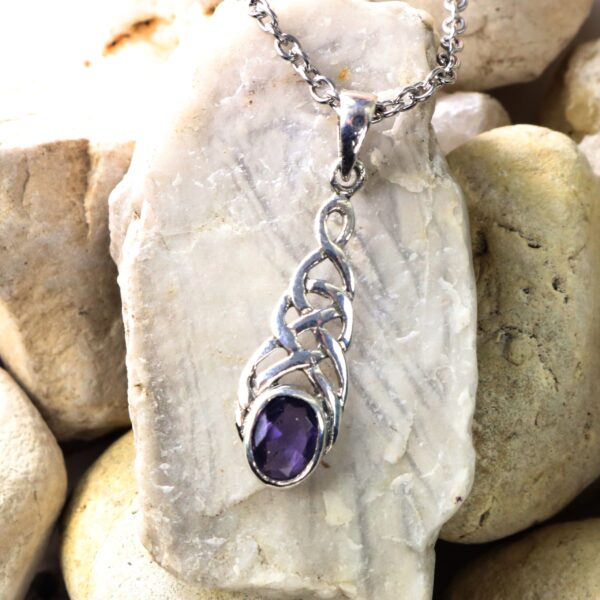 An *Amethyst Celtic Knot Necklace* featuring a stunning Amethyst pendant delicately resting on a bed of rocks.