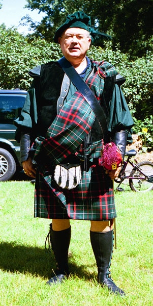 A man in a Heavy Weight 16oz Premium Wool Ancient Kilt standing in a grassy area.