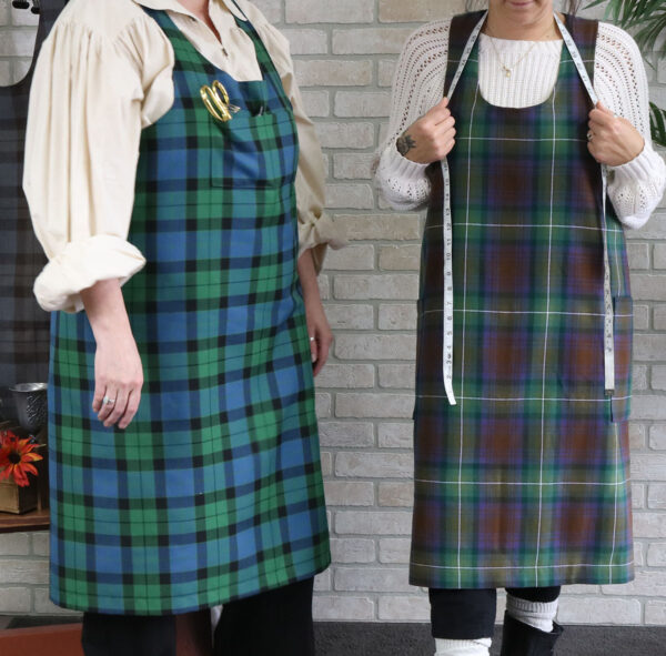 Two women in Tartan Cross Back Aprons - Homespun Wool Blend made from a homespun wool blend tartan standing next to each other.