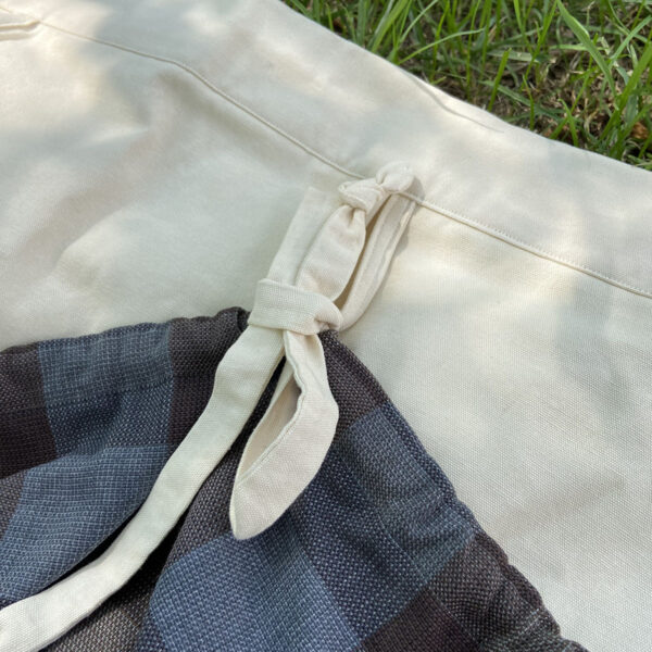 A close up of a pair of Tartan Gathering Apron - Homespun Wool-Blend pants in the grass.