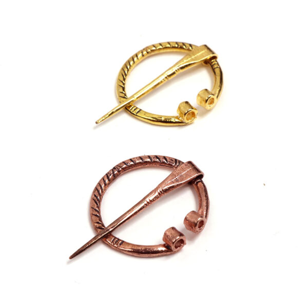 A mini pair of gold and copper Mini Penannular Brooches on a white surface.