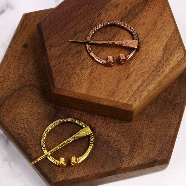 Two Mini Penannular Brooches on a wooden tray.