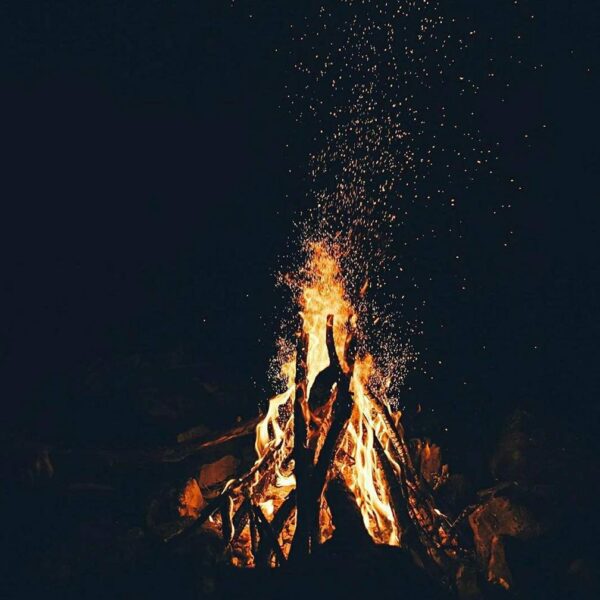 A bonfire in the dark with sparks coming out of it.