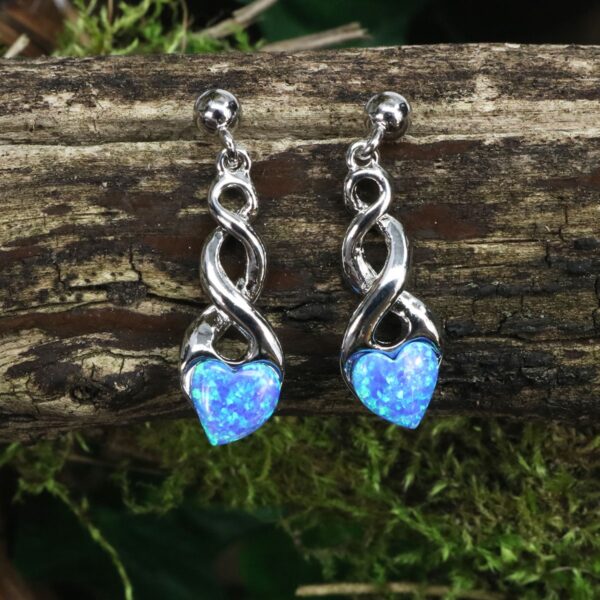 A pair of blue Tree of Life earrings resting delicately on top of some moss.