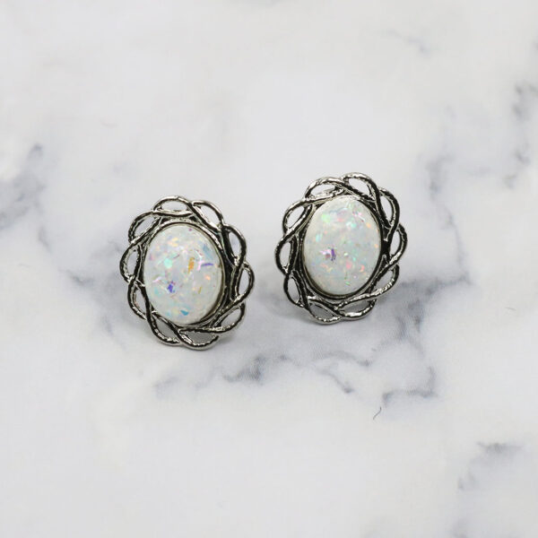 A pair of white Opal Knot stud earrings on a surface.