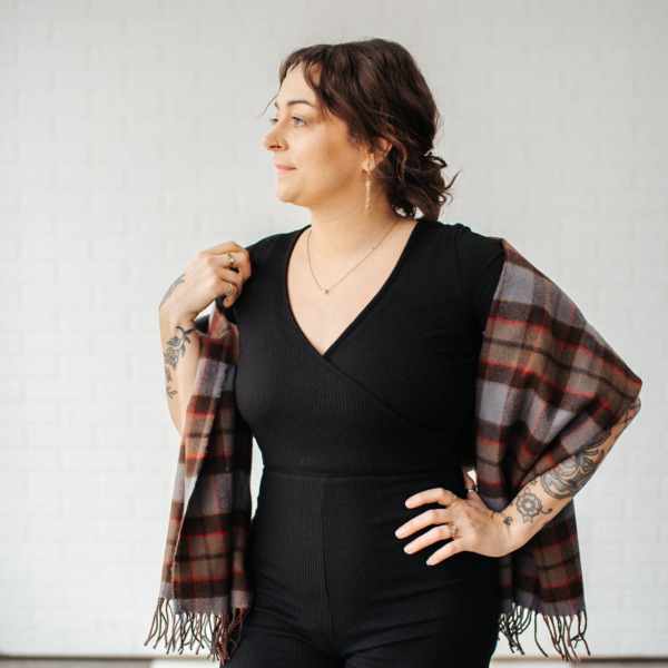 A woman in a black jumpsuit wearing an OUTLANDER Stole Authentic Premium Wool Tartan.